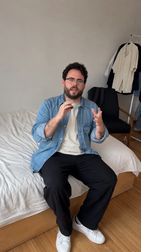 Hombre mostrando un conjunto casual sentado en su habitación